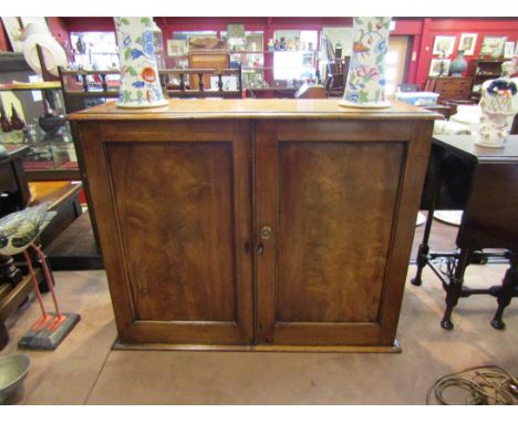 Circa 1840 a flame mahogany wall hanging two door cupboard with key opening to reveal a three drawer and shelf interior, 60cm