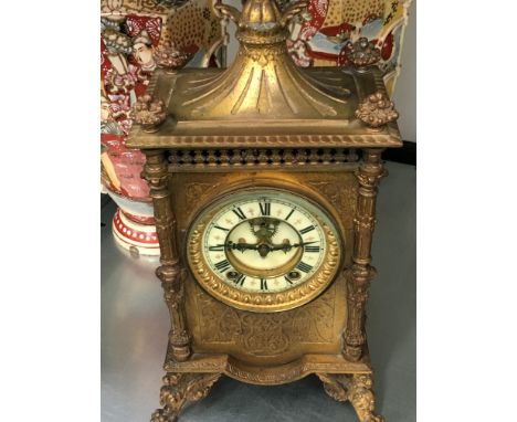 A late 19th century brass cased Ansonia clock decorated to sides and back with classical figures resting on four feet ( finia