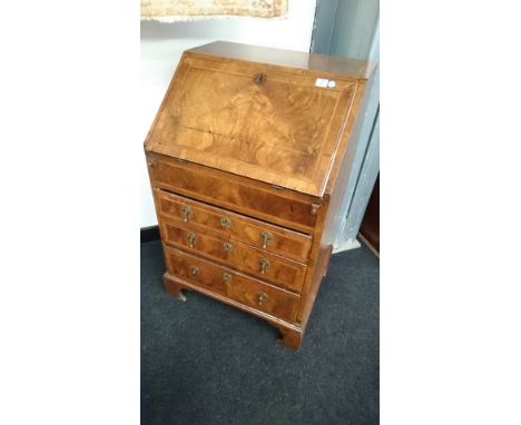 A small ladies' burr walnut three drawer bureau resting on bracket feet with herringbone inlay to top door and drawer fronts 
