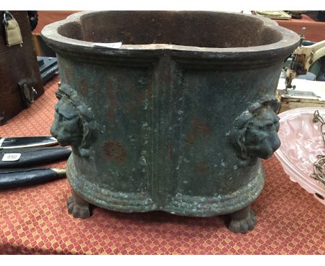 A very heavy 19th century cast iron planter with Lion Mask motifs resting on paw feet.