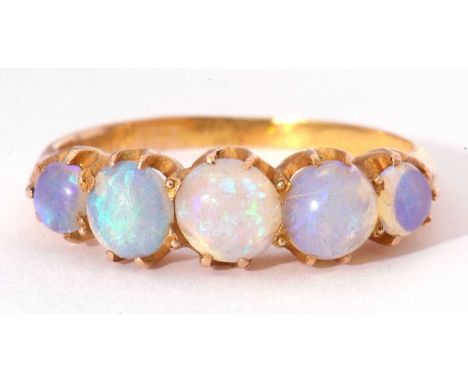 Five stone opal ring, line set with graduated round cabochon cut opals, set in a mid-grade yellow metal mount, size M/N