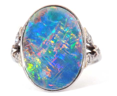 Opal and diamond ring, the oval shaped flat opal bezel set and raised between small diamond set split shoulders, stamped 18ct