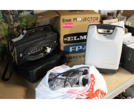 An Elmo Delux projector together with an Oreck XL vacuum attachment, a Powerful projector, and a bag of attachments