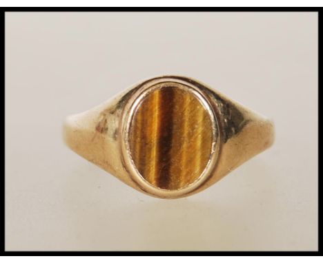 A 9ct gold ring set with an oval tigers eye panel to the head. Marks rubbed. Weight 3.8g. Size T.&nbsp;