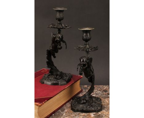 A pair of 19th century dark patinated bronze mantle sticks, cast with cherubs flying amongst stylised acanthus leaves, circul