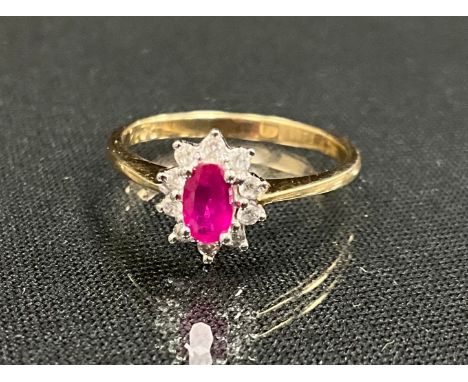 A diamond and pink stone possibly ruby cluster ring, oval pink stoen surrounded by ten round brilliant cut diamonds, 9ct gold