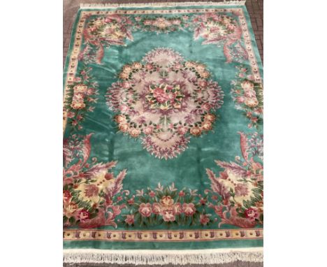 A Chinese Shensi deep pile woolen rug, in rich jade green, with floral medallion and corners in tones of pink, green, and cre