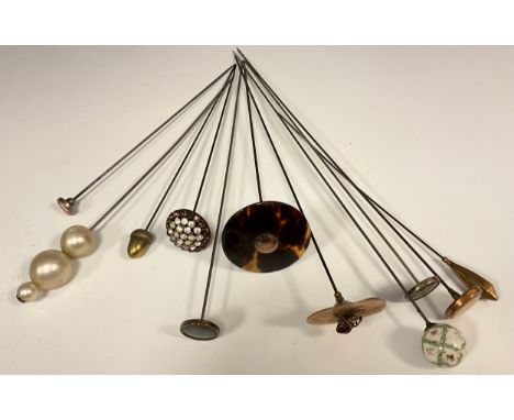 A collection of eleven Victorian and later hat, scarf and stick pins, including hand painted floral globular lattice ball, to