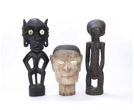 Tribal interest, carved wooden head, possibly Indonesian with inset bone eyes, together with two other standing tribal figure