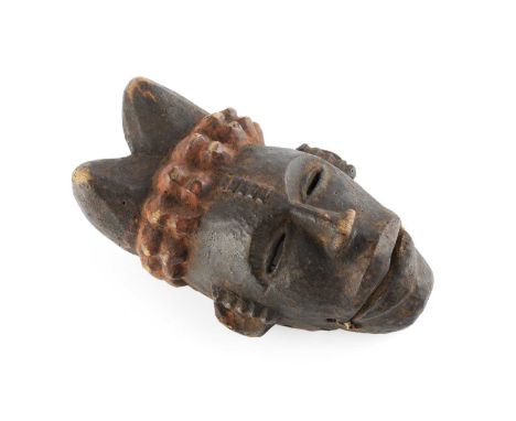 An African wooden Aanang Ekpo puppet mask with moveable jaw, the horns with red pigment, 20cm