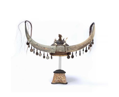 Tribal interest, carved wooden helmet possibly Indonesian, with carved buffalo horns and draping shells topped by wooden figu