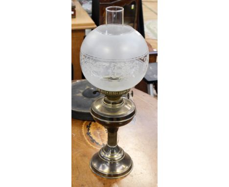 A brass oil lamp with frosted glass globe shade