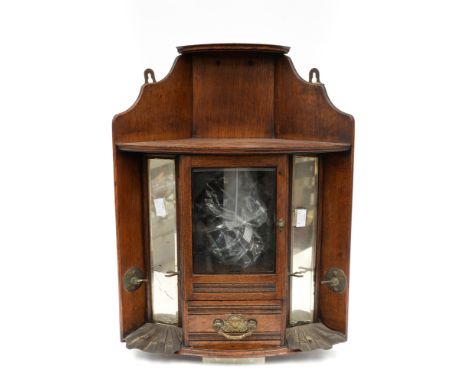 A smokers cabinet, housing two mirrors and bevelled glass door, with a Triang Bakelite pipe, a carved pipe and other smoking 