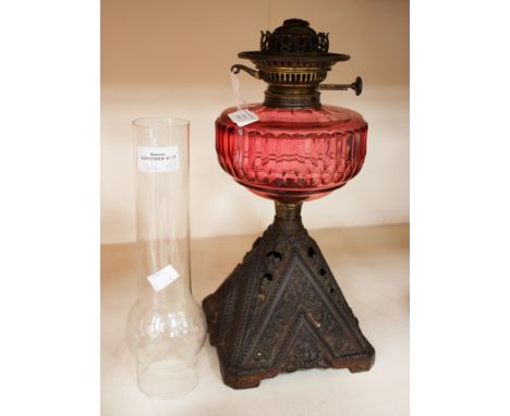 An oil lamp cast iron base with cut cranberry glass reservoir, in working order, with glass funnel.