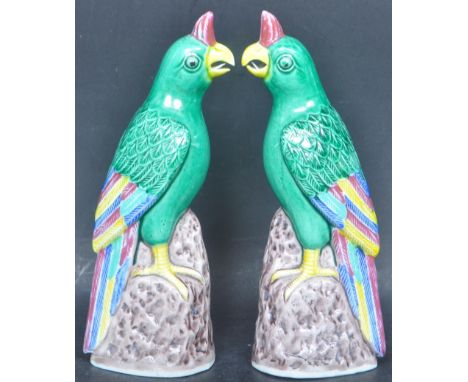 A pair early 20th century Chinese oriental ceramic parrot figures in the Kangxi manner with stamp to base. Measures 17cm tall