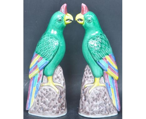 A pair early 20th century Chinese oriental ceramic parrot figures in the Kangxi manner with stamp to base. Measures 17cm tall