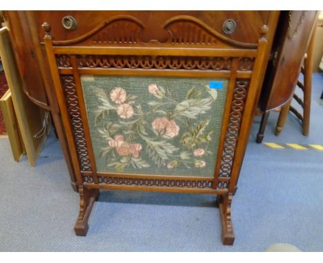 An Edwardian mahogany fire screen with pierced decoration and floral needlework panel