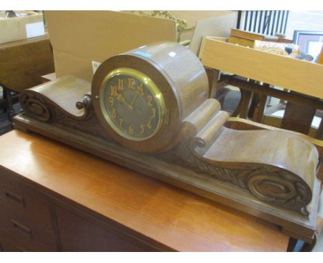 An early 20th century large oak cased 8 day striking mantle clock having a silvered dial and a carved floral and scroll case 