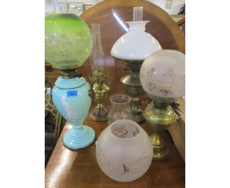 Four oil lamps to include a French gilt metal and opaline glass oil lamp of vase shape with later green etched glass shade