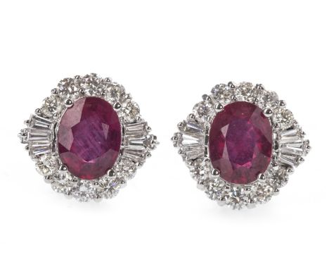 PAIR OF TREATED RUBY AND DIAMOND EARRINGS, each set with a treated oval ruby, within a halo of round brilliant and tapered ba