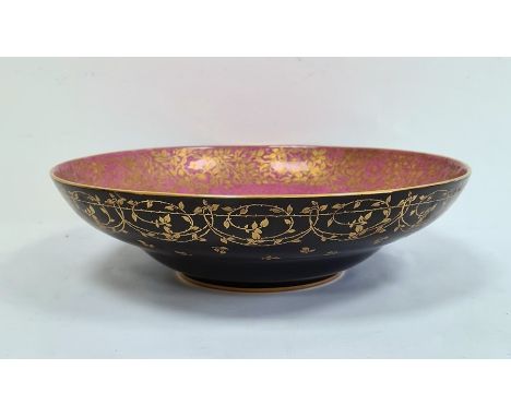 Royal Worcester porcelain shallow bowl, matt black glazed with gilt foliate border to exterior, mottled pink interior with gi