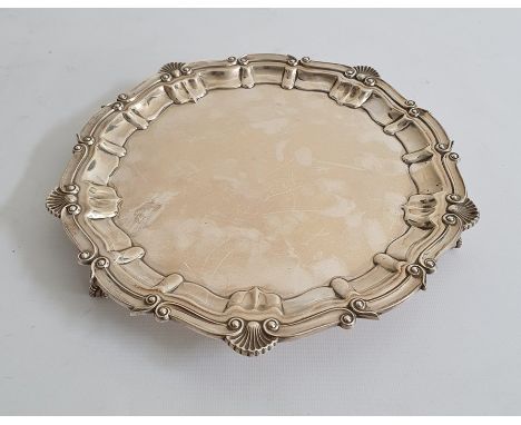 Early 20th century silver salver, circular with scroll and shell decoration, on three claw and ball feet, Birmingham, maker's