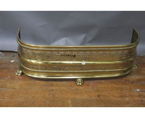 A GEORGIAN STYLE PIERCED BRASS SHORT FENDER, the bobbin borders between foliate pierced panels on claw feet,31cms x 89cms.