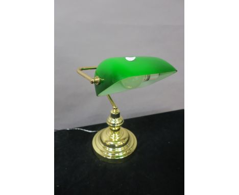 A BRASS DESK LAMP, with green and opaline glass shade raised on circular spreading foot, 36cms high.
