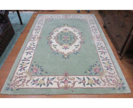 A RECTANGULAR WOOL RUG the green ground decorated with flower heads with a central green panel flanked by a white border  296