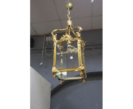 A BRASS HALL LANTERN, of rectangular form with bevelled glass panel and mask capitals with scrolled arms.