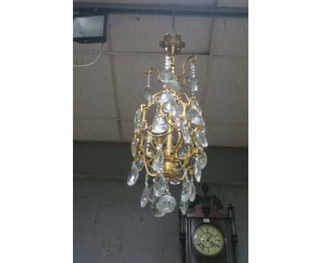 A CONTINENTAL STYLE GILT BRASS AND CUT GLASS FOUR LIGHT CHANDELIER, the scrolled arms hung with diamond cut pendants.