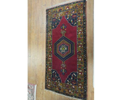 A WOOL RUG, the wine ground with central octagonal panel containing palmettes and  hooks, within a conforming border,102cms x