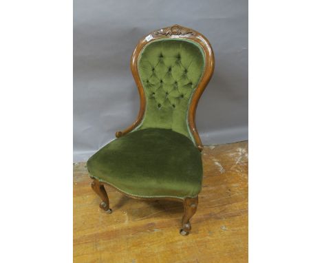 A VICTORIAN MAHOGANY CARVED LADIES ARMCHAIR the waisted back headed by a foliate cartouche with buttoned upholstered panel se