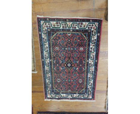 A WOOL RUG, the light pink ground with central panel, containing palmettes and hooks within a conforming border. 122cms x 80c