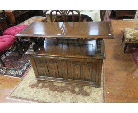 AN EARLY 20th CENTURY OAK MONKS' BENCH, the rectangular hinged top raised on carved lion supports with hinged seat, the friez