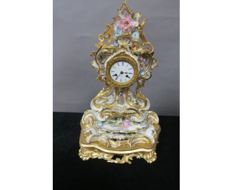 A FRENCH GLAZED PORCELAIN MANTLE CLOCK the profusely scrolled frame with gilded highlights and applied with coloured flower h