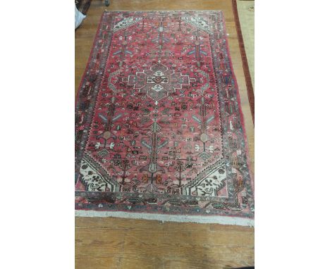 A GOOD ORIENTAL WOOL RUG the light pink ground with central panel filled with palmettes, lozenges and hooks within a conformi