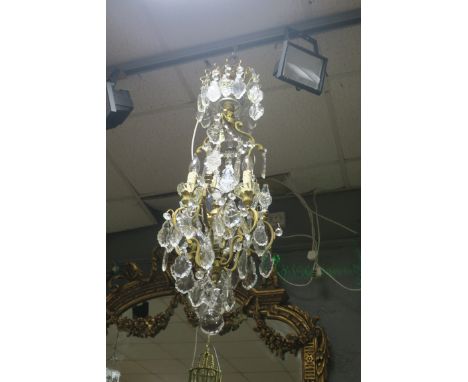 A CONTINENTAL STYLE GILT BRASS AND CUT GLASS FOUR LIGHT CHANDELIER, the flying C scrolled arms hung with diamond cut pendents