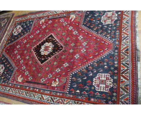 A FINE WOOL RUG, the indigo and red ground with central geometric panel within a conforming border 310cms x 212cms
