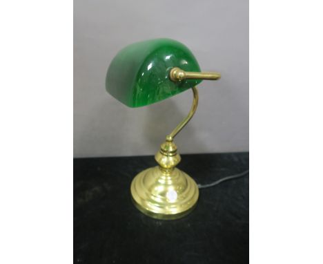 A BRASS DESK LAMP, the green and opaline glass shade with scroll arm raised on circular spreading foot,35cms high.