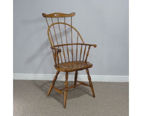 A 20th century ash and elm windsor Armchair, with a shaped comb-back and scrolled arms, raised on shaped seat and turned supp