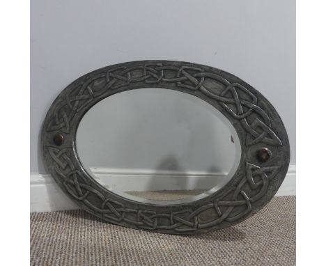 A Scottish school Arts and Crafts pewter oval Mirror, the frame embossed with a Celtic knot design and mounted with two brown