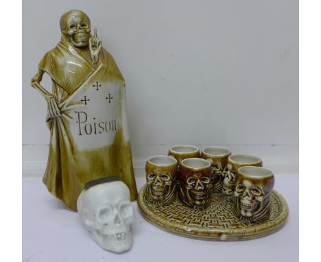 A Schafer skull matchstriker and an eight piece ceramic 'poison' flask, cups and tray