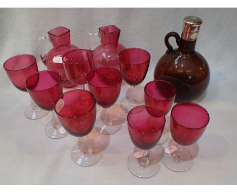 A 19TH CENTURY BOTTLE WITH ENGINE-TURNED PLATED TOP a pair of cranberry glass jugs, and nine cranberry wineglasses