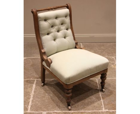 A Victorian honey oak framed low seat chair, with a turned top rail over a button back, sprung straight front seat upon turne