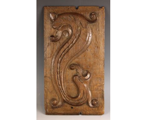 A 17th century carved oak panel, possibly Welsh, carved in relief with a scrolling sea horse upon a chamfered panel, 40cm x 2