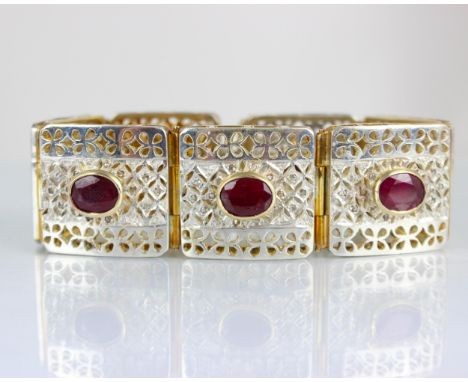 A contemporary two tone panel bracelet, the seven square openwork panels set in white metal with diamond highlights, with rai
