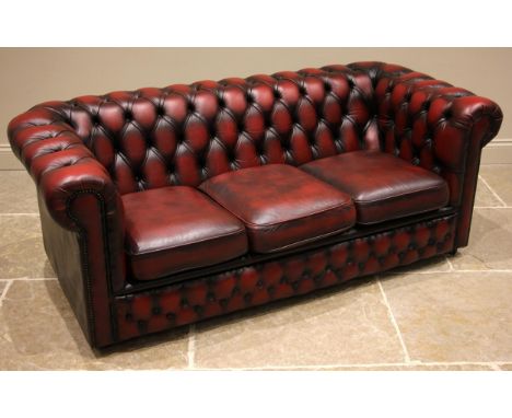 An oxblood red leather Chesterfield sofa and conforming armchair, late 20th century, both of typical deep set form with butto