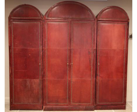 An impressive and large red leather wardrobe, mid 20th century, of triple arched form, the pair of central doors, flanked by 