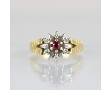 An 18ct yellow gold diamond ring, the central round cut untested ruby raised above white metal and diamond set stylised clust
